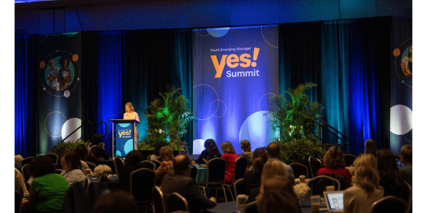 photo of a speaker presenting to a crowded room at the YES! Summit